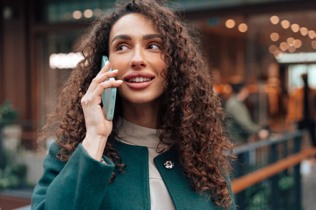 Young woman talking on mobile phone while walking in the city close up